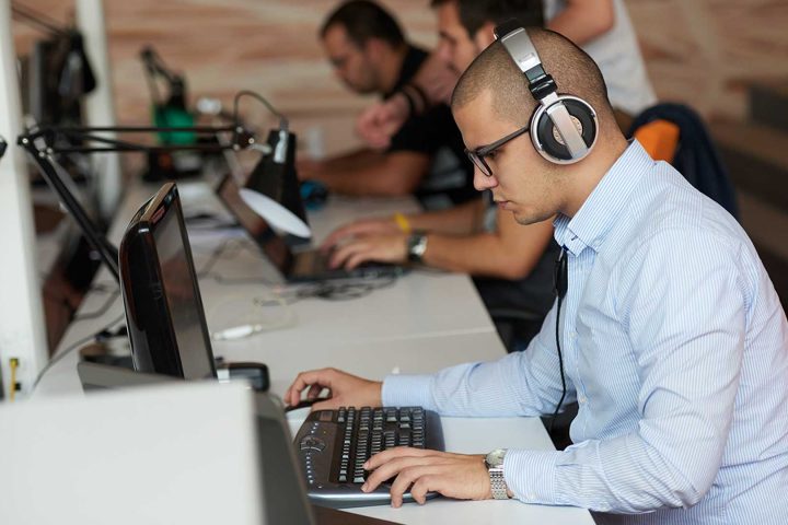 man working on a laptop, wearing headphones